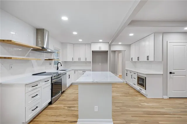 a large kitchen with stainless steel appliances granite countertop a stove top oven a sink and a refrigerator