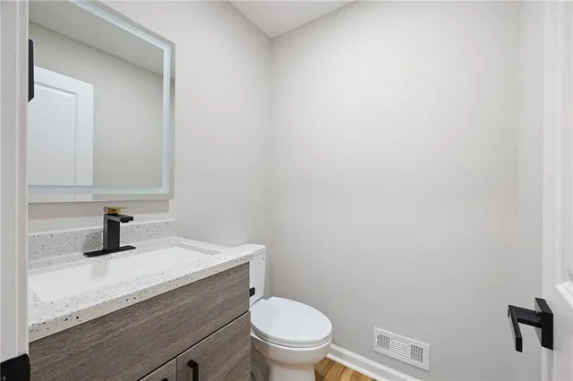 a bathroom with a granite countertop toilet sink and mirror