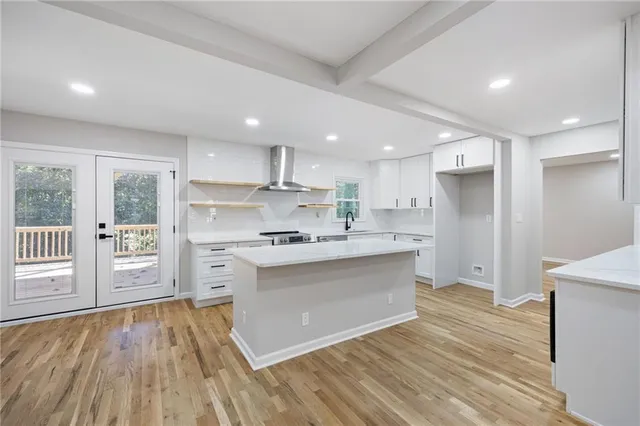a kitchen with stainless steel appliances granite countertop a stove a sink and white cabinets with wooden floors