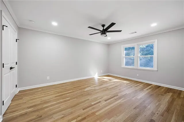 a view of empty room with wooden floor and fan