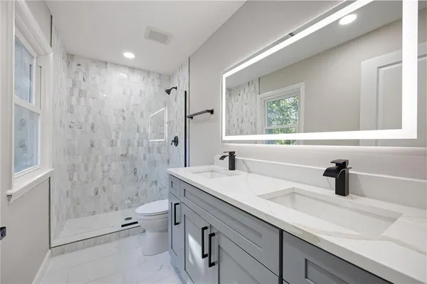 a bathroom with a sink a toilet and shower