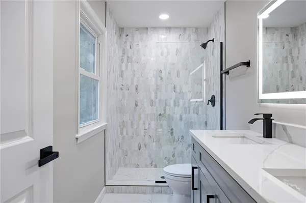 a bathroom with a granite countertop sink a toilet and shower