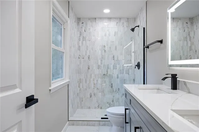 a bathroom with a granite countertop sink a toilet and shower