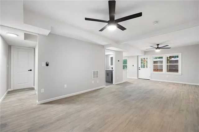 a view of an empty room with window and wooden floor
