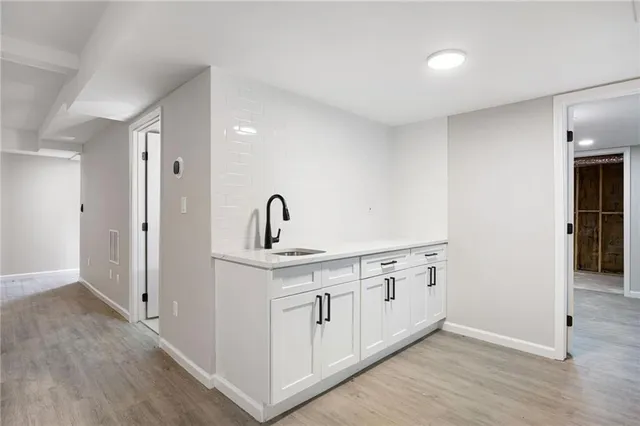 a kitchen with white cabinets a sink and wooden floor