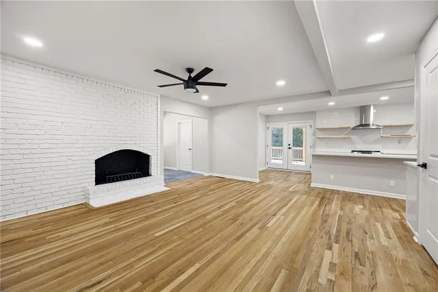a view of kitchen and empty room with wooden floor