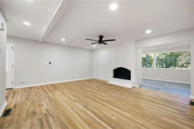 a view of an empty room with a fireplace and wooden floor