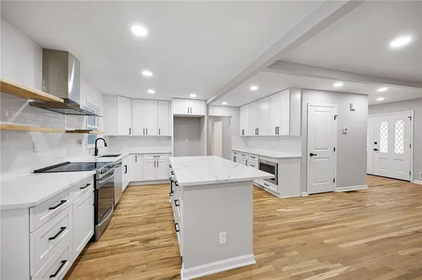 a large kitchen with stainless steel appliances kitchen island a large counter top and a stove top oven
