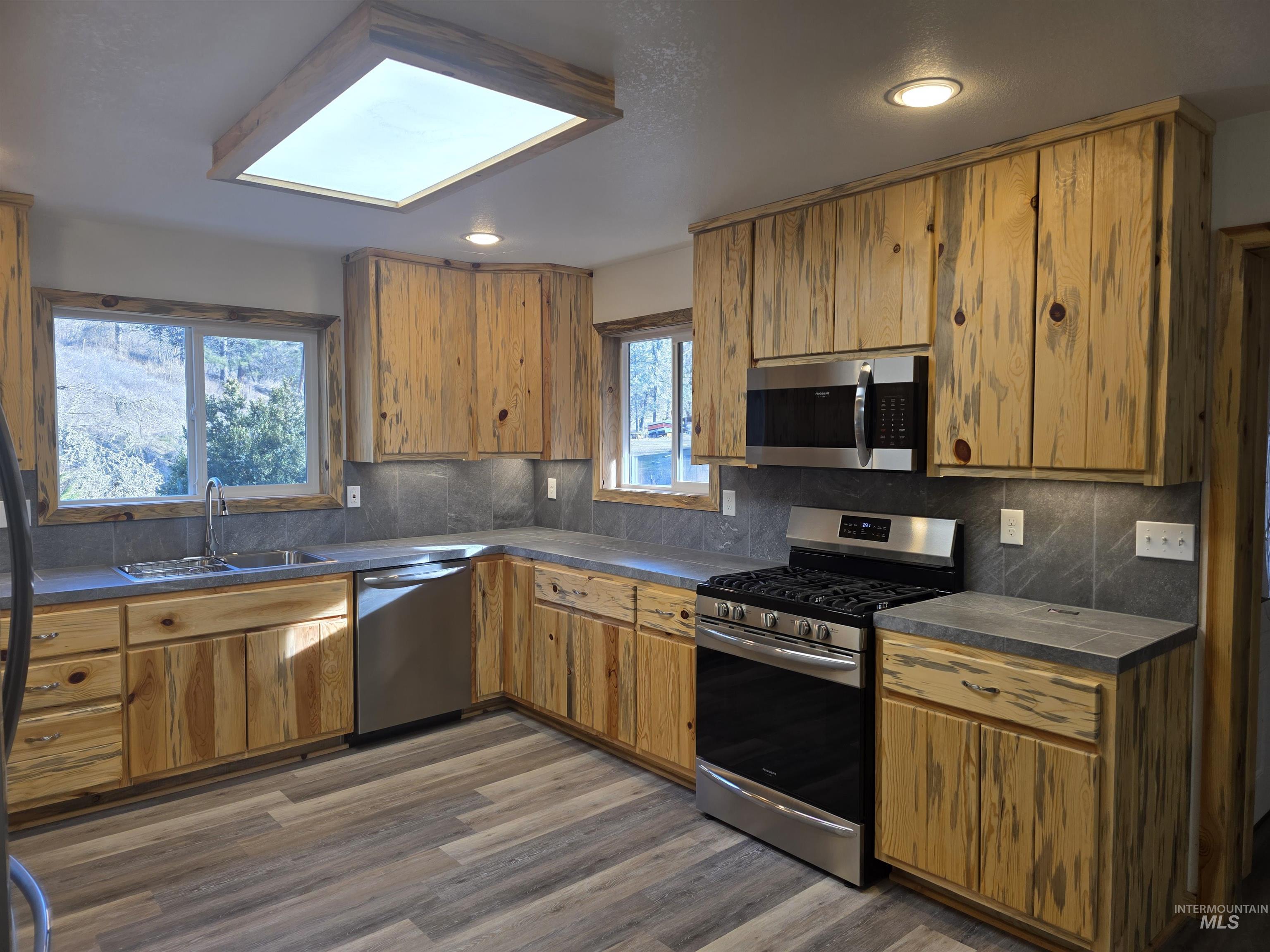 4157 Highway 12 Kamiah, ID 83536 - Photo 13 of 40 Kitchen featuring stainless steel appliances, dark countertops, dark wood-type flooring, tasteful backsplash, and wood finish cabinetry