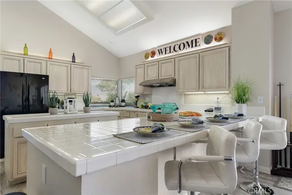 a kitchen with stainless steel appliances a sink a stove a refrigerator cabinets and chairs