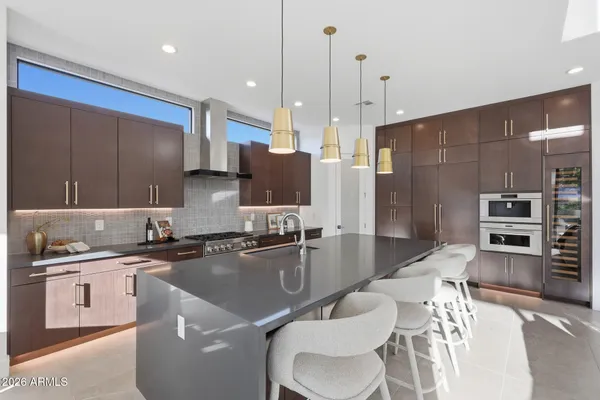 a kitchen with a sink stainless steel appliances and chairs