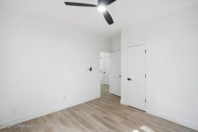 an empty room with wooden floor cabinet and windows