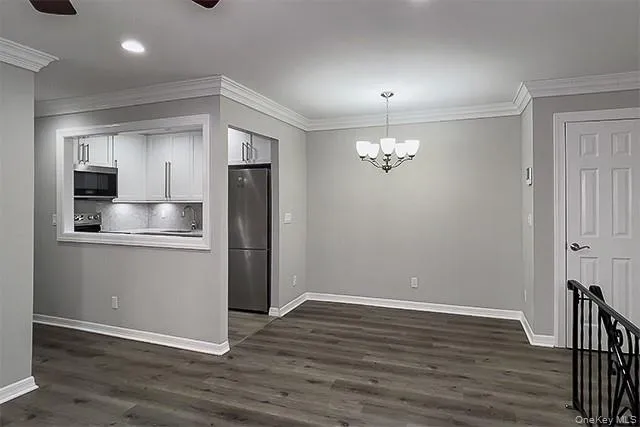a view of kitchen and empty room with wooden floor