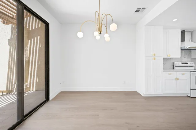 en empty room with kitchen view and wooden floor