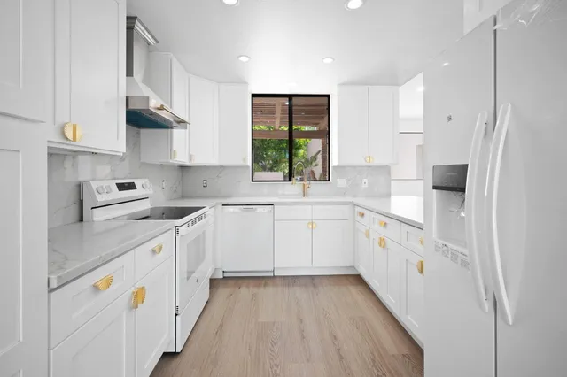 a kitchen with cabinets appliances a sink and a window