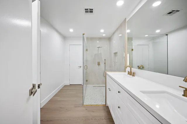 a spacious bathroom with a double vanity sink a mirror and a shower