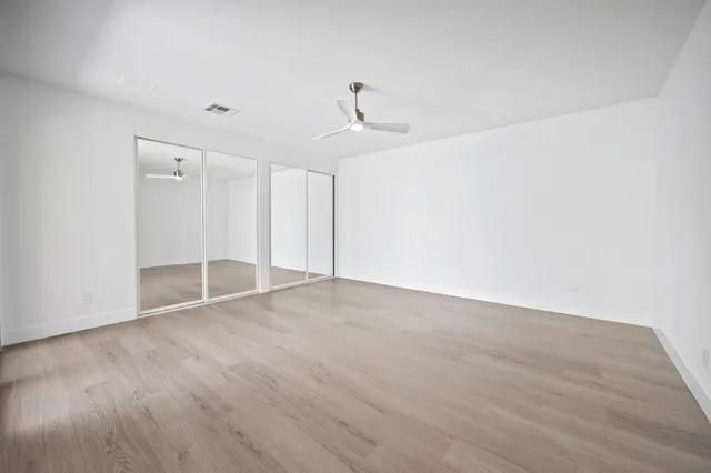 a view of empty room with wooden floor and ceiling fan