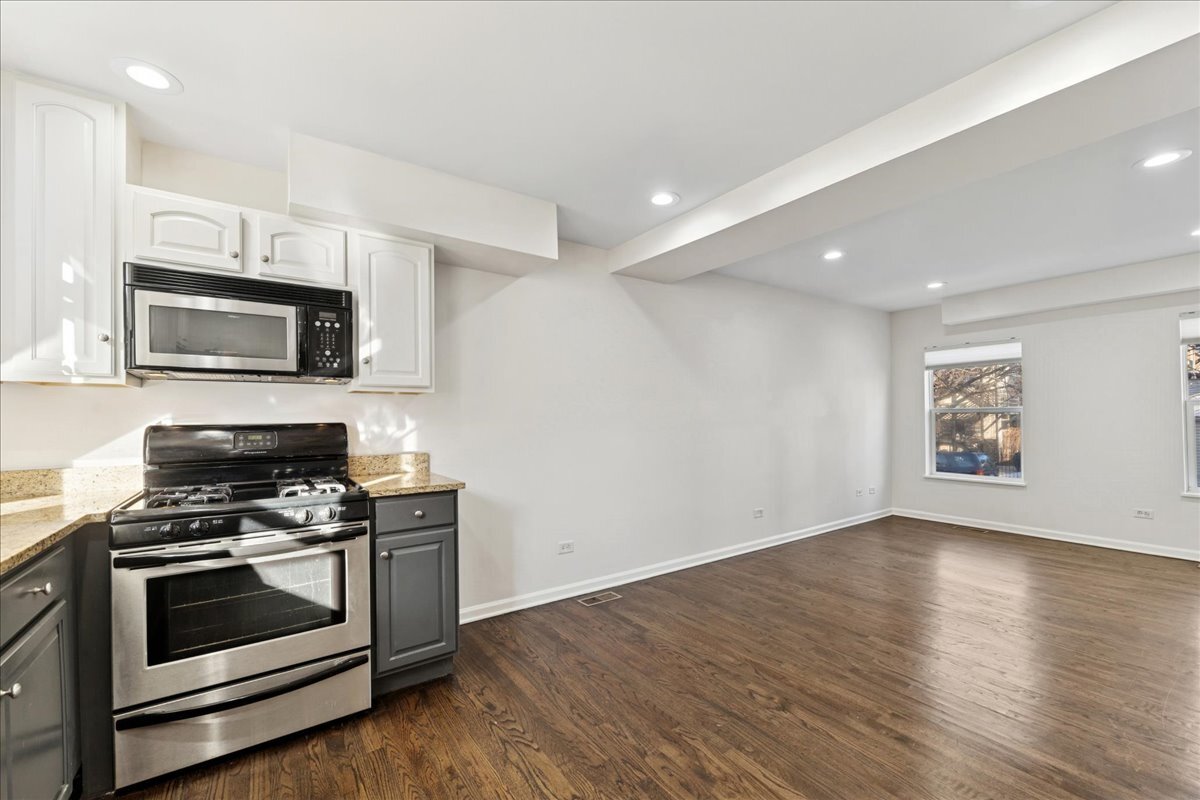648 North Bishop Street, Unit S Chicago, IL 60642 - Photo 8 of 23 a kitchen with granite countertop a stove top oven a sink dishwasher a microwave oven with cabinets and wooden floor