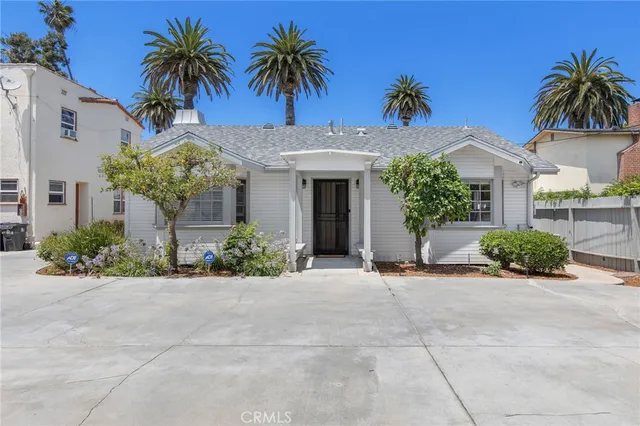 front view of a house with a yard and palm trees