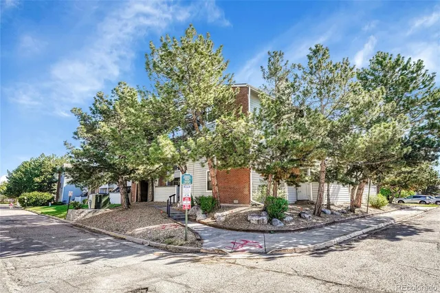 a front view of a house with garden and tree