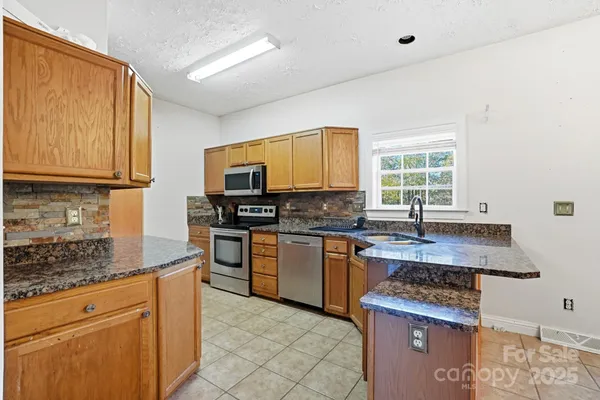 a kitchen with stainless steel appliances granite countertop a stove a sink dishwasher and a microwave oven with cabinets
