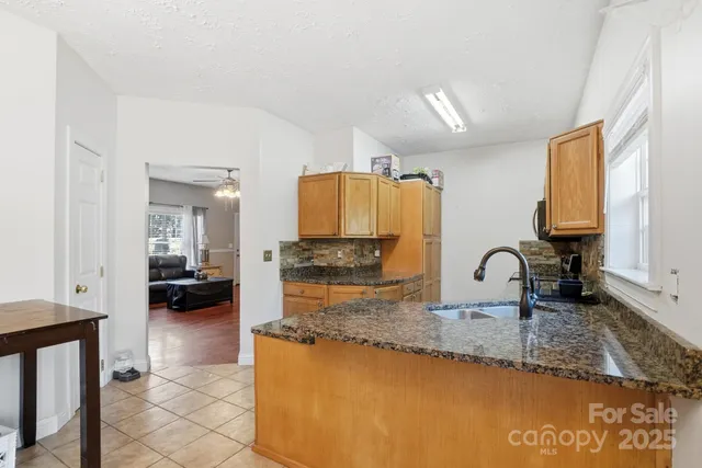 a kitchen with granite countertop a sink a stove and cabinets