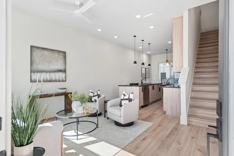 a living room with furniture a wooden floor and kitchen view
