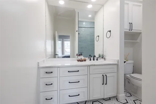 a bathroom with a granite countertop toilet sink and mirror