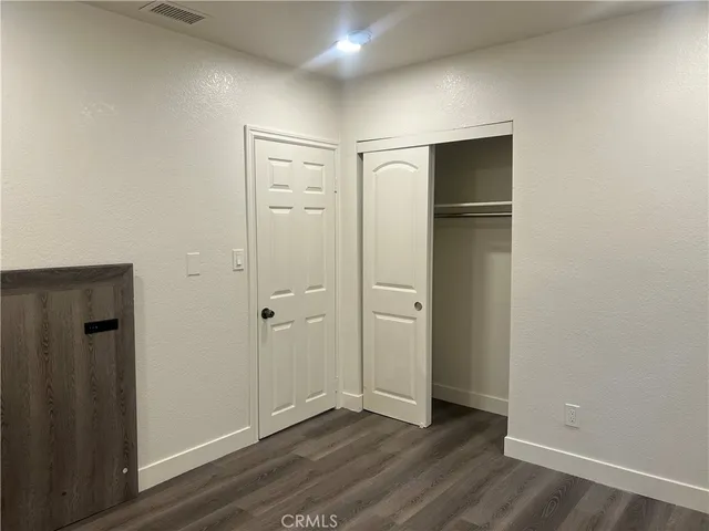 an empty room with wooden floor and closet area