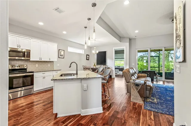 a view of a kitchen with cabinets stainless steel appliances and a large window