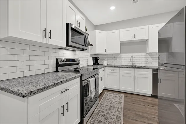 a kitchen with stainless steel appliances granite countertop a sink stove and cabinets