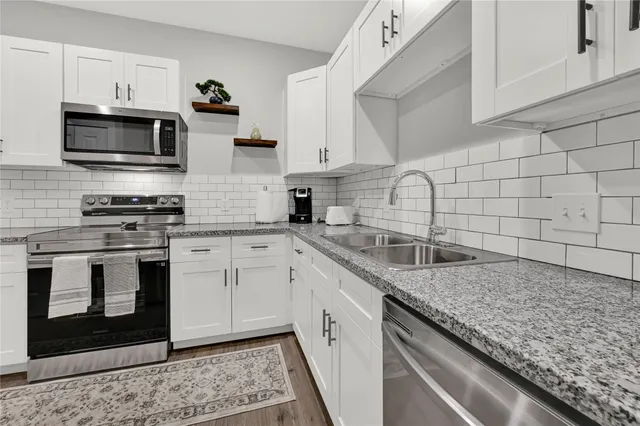 a kitchen with stainless steel appliances granite countertop a sink stove and microwave