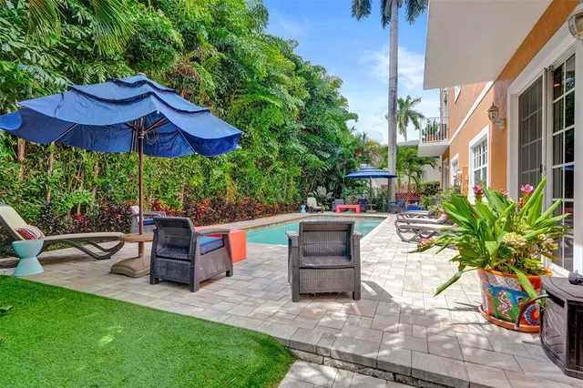 a view of a patio with couches table and chairs under an umbrella