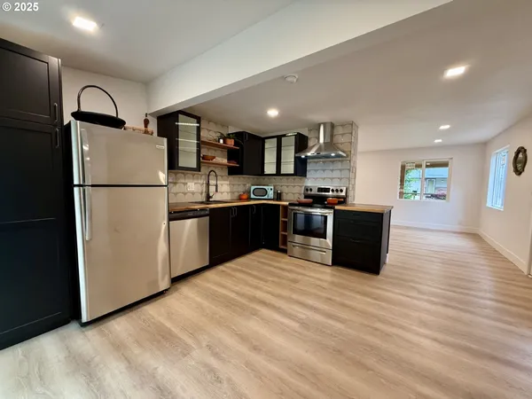 a kitchen with stainless steel appliances granite countertop a refrigerator a sink a stove and a microwave