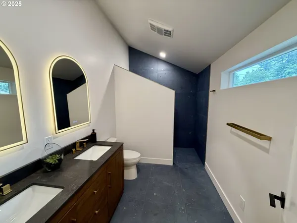 a bathroom with a double vanity sink toilet and mirror