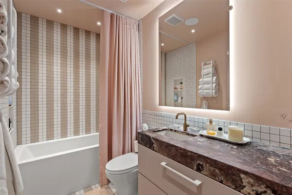 a bathroom with a granite countertop sink a toilet a mirror and shower