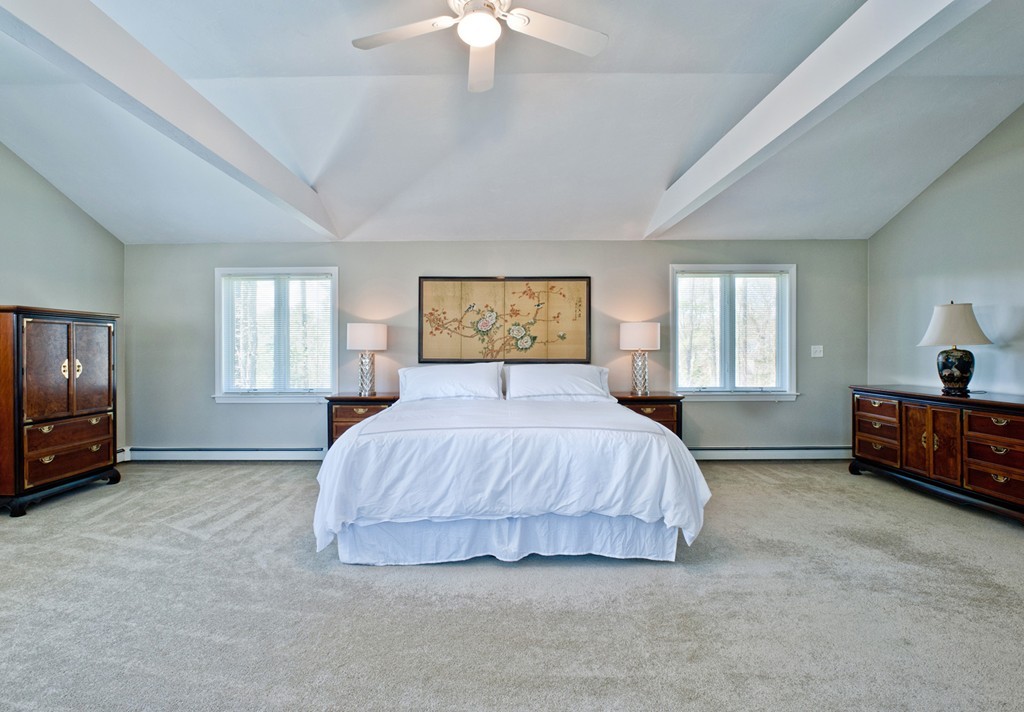 79 Linden Lane Hanover, MA 02339 - Photo 15 of 30 a spacious bedroom with a bed a couch and a chandelier