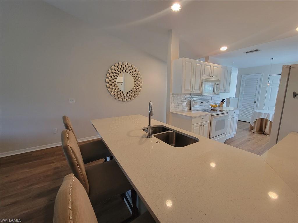 4950 Deerfield Way, Unit D202 Naples, FL 34110 - Photo 8 of 21 a kitchen with a sink a stove cabinets and wooden floor