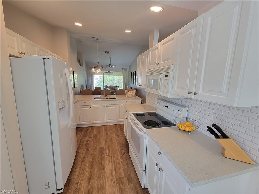 4950 Deerfield Way, Unit D202 Naples, FL 34110 - Photo 10 of 21 a kitchen with white cabinets and white appliances