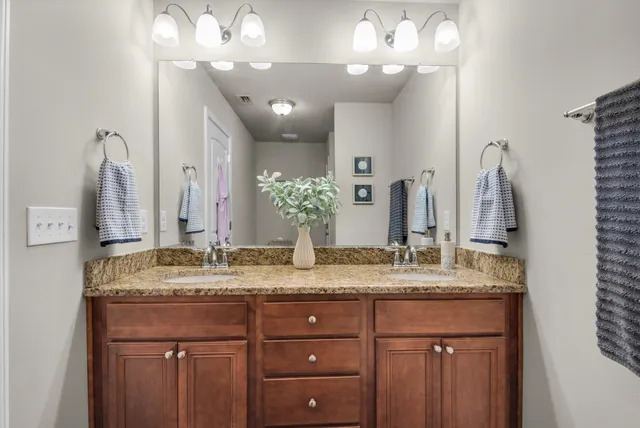 a bathroom with a granite countertop double vanity sink and a mirror