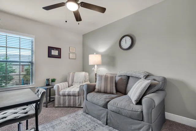 a living room with furniture a ceiling fan and a window