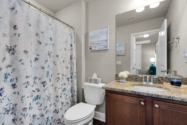 a bathroom with a granite countertop sink mirror vanity and toilet