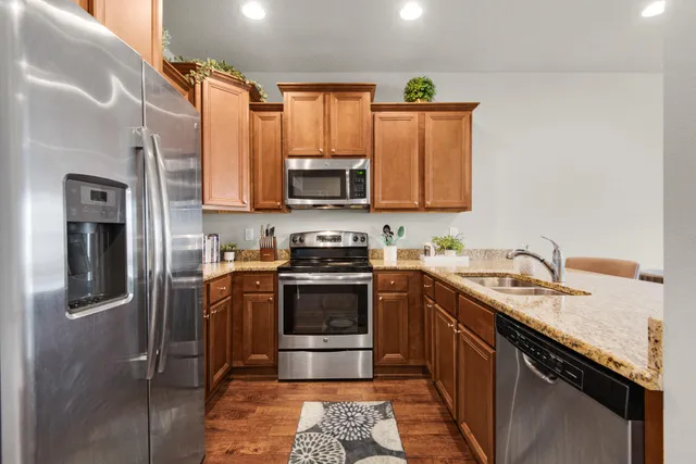 a kitchen with stainless steel appliances granite countertop a sink stove and refrigerator