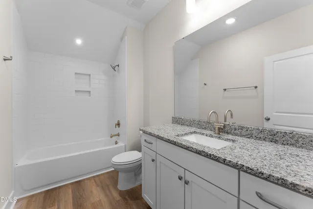 a bathroom with a granite countertop sink a toilet and bathtub