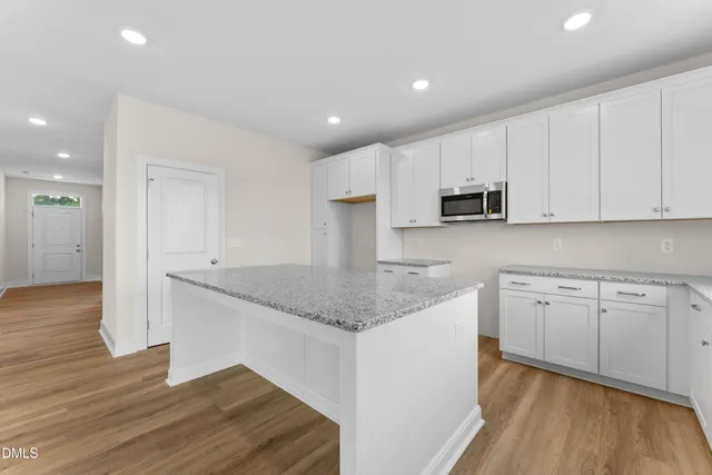 a kitchen with kitchen island granite countertop a sink cabinets and wooden floor