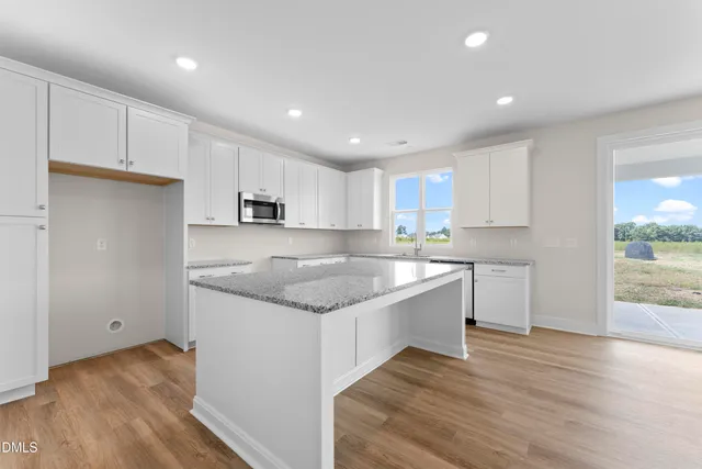 a kitchen with granite countertop white cabinets and wooden floor