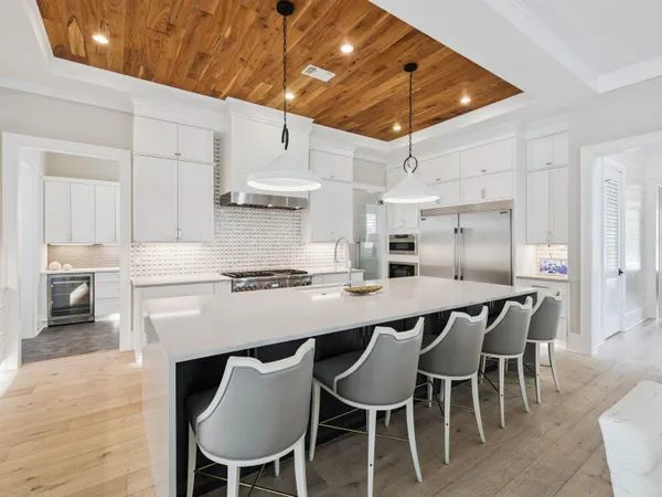 a kitchen with stainless steel appliances a dining table chairs sink and cabinets