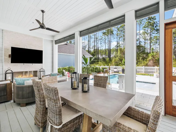a living room with furniture a flat screen tv and floor to ceiling windows