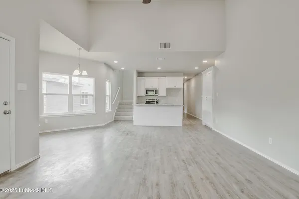 a view of a electric appliances in kitchen and empty room with wooden floor