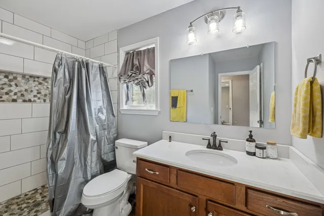 a bathroom with a granite countertop sink toilet and shower